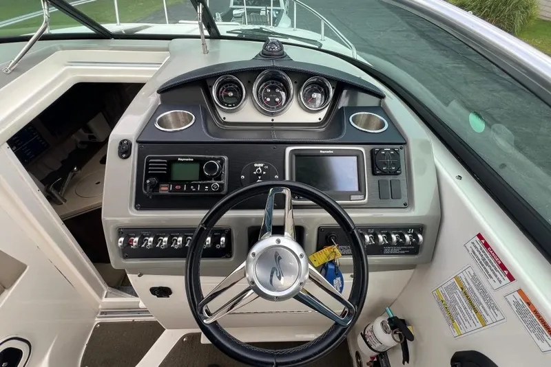 Slide: The Image of 2015 Sea Ray 260 Sundancer dashboard with steering wheel and navigation controls. - 12