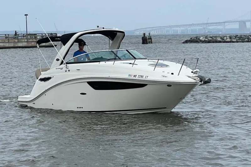 Slide: The Image of 2015 Sea Ray 260 Sundancer boat cruising on a calm waterway near a bridge. - 6