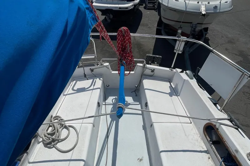 Slide: The Image of Catalina 22 sailboat cockpit with blue cover and red ropes, docked among other boats. - 12