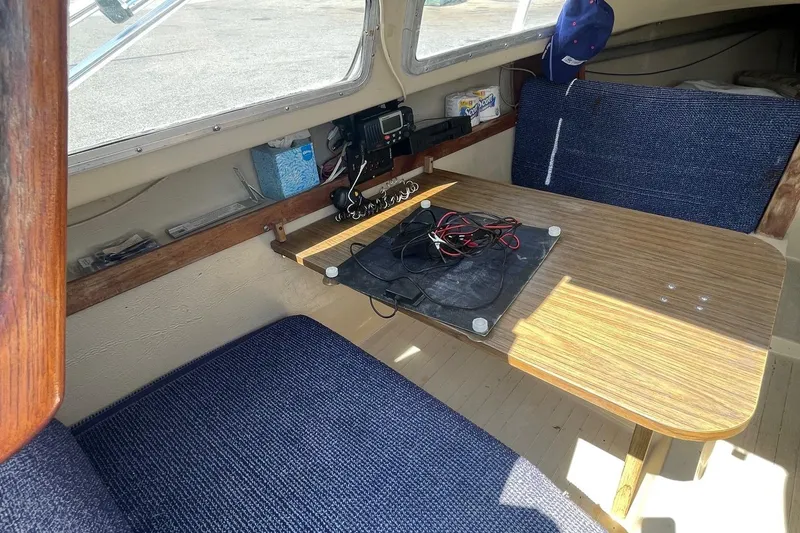 Slide: The Image of Interior of a Catalina 22 sailboat with a wooden table and blue seating. - 9