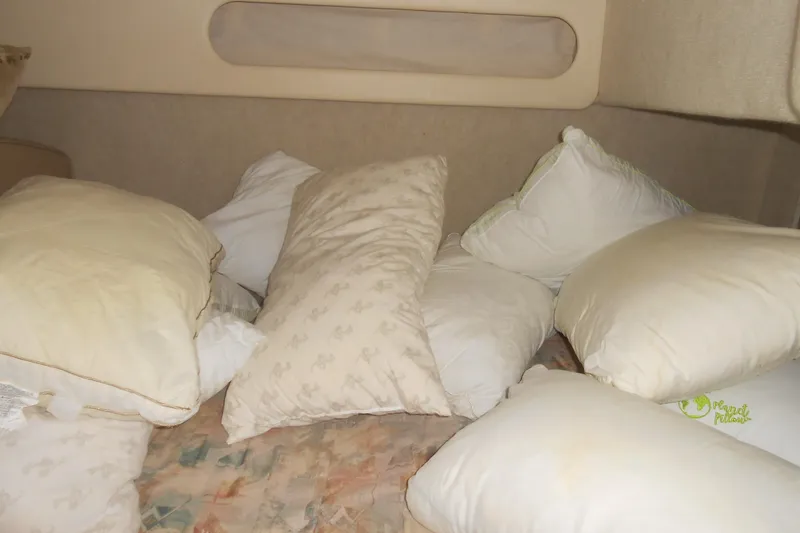 Slide: The Image of Interior of 1999 Bayliner 3055 Ciera with multiple pillows on a bed. - 14