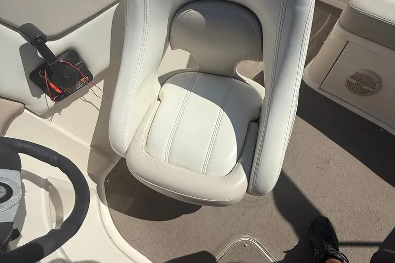 Slide: The Image of Interior of a 2005 Bryant 214 boat featuring a white captain's chair and steering wheel. - 14