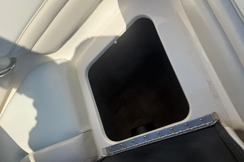 Slide: The Image of Boat storage compartment in a 2005 Bryant 214, featuring white interior and metal hinge. - 19