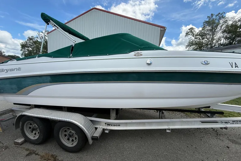 Slide: The Image of 2005 Bryant 214 boat on trailer with green cover, parked outdoors. - 3