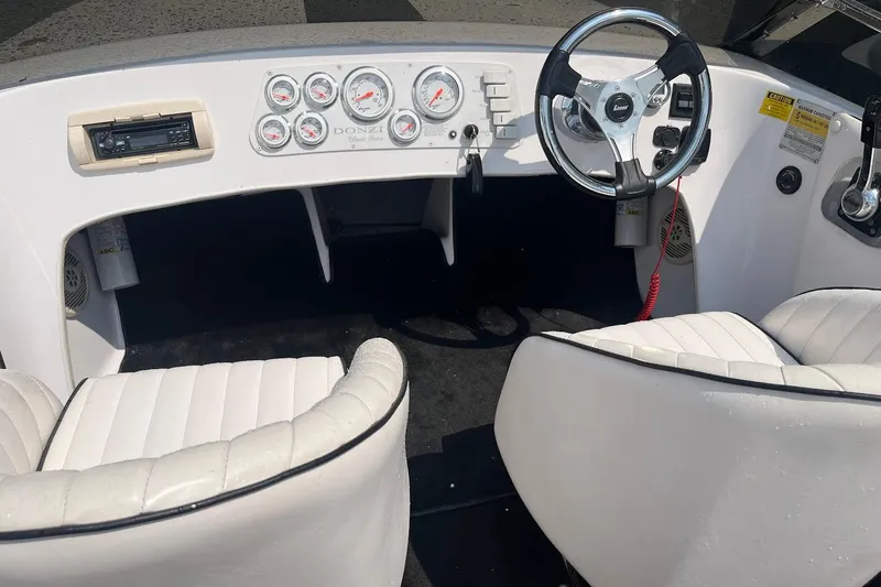 Slide: The Image of Interior of a 1999 Donzi 22 Classic boat with white seating and dashboard gauges. - 10