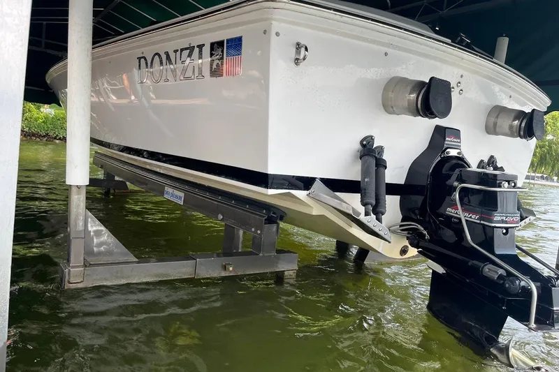 Slide: The Image of 1999 Donzi 22 Classic boat on lift, showcasing rear view and engine details. - 16