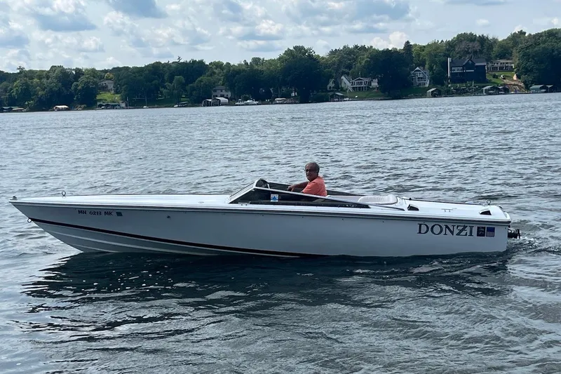 Slide: The Image of 1999 Donzi 22 Classic speedboat cruising on a lake with scenic shoreline. - 2