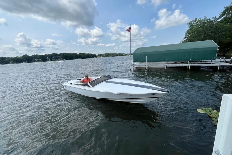 Slide: The Image of 1999 Donzi 22 Classic boat on a lake near a dock, under a partly cloudy sky. - 3