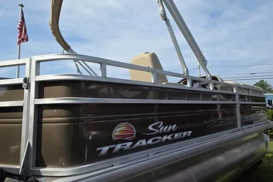 The Image of 2025 Sun Tracker Sportfish™ 20 DLX pontoon boat on trailer, American flag in background. - 0