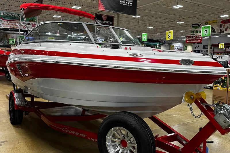Slide: The Image of 2024 Crownline 200SS boat with red and white exterior on display indoors. - 2