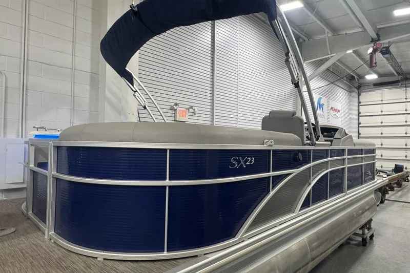 Slide: The Image of 2020 Bennington 23 SXPD pontoon boat in a showroom, featuring sleek blue design. - 3