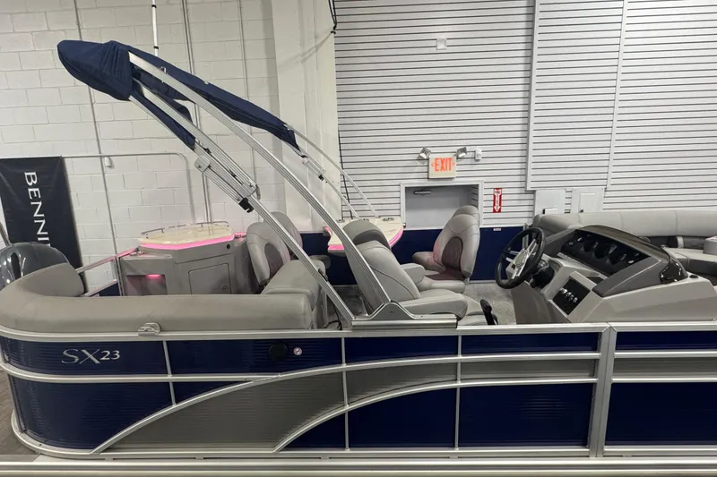 Slide: The Image of 2020 Bennington 23 SXPD pontoon boat with blue and gray interior, displayed indoors. - 6