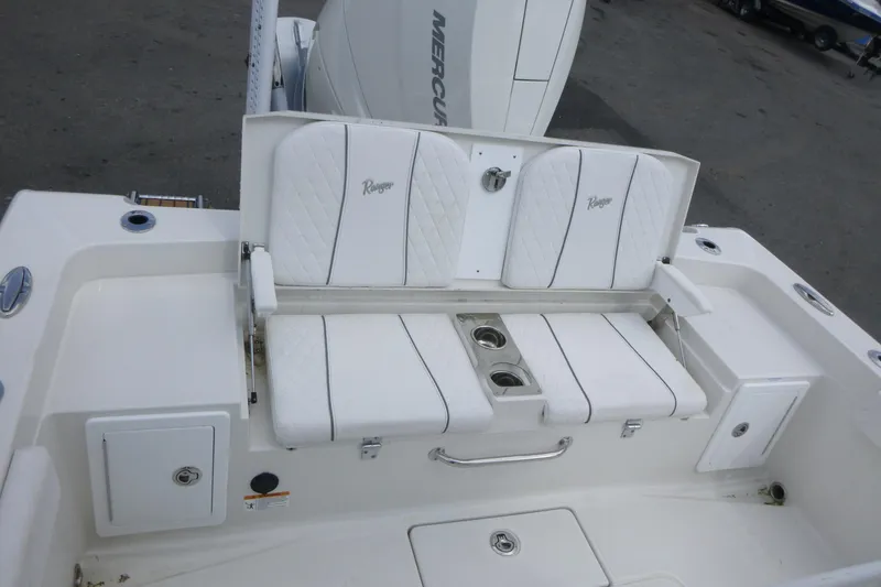 Slide: The Image of 2024 Ranger 2660 Bay boat with white cushioned seating and storage compartments. - 15