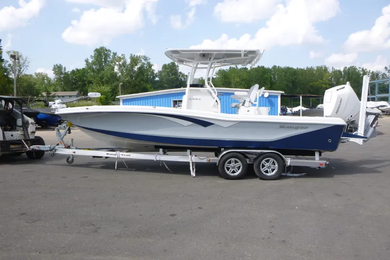 Slide: The Image of 2024 Ranger 2660 Bay boat on trailer, blue and white design, parked outdoors. - 3