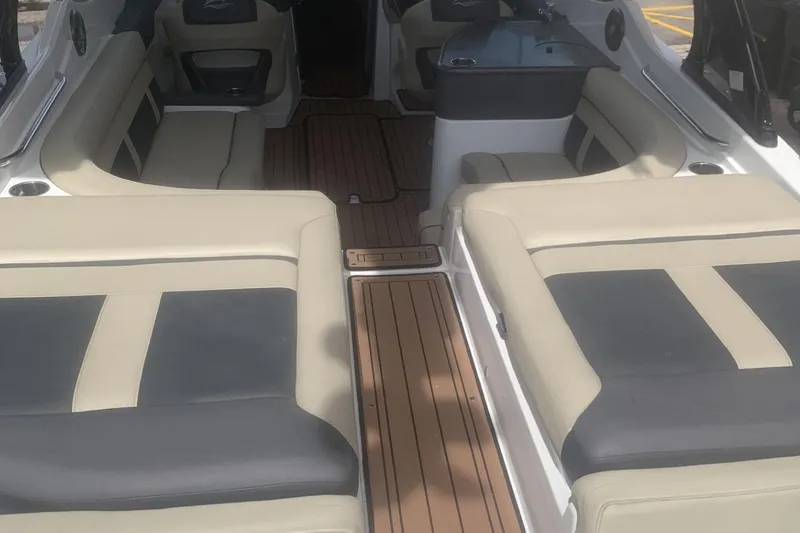 Slide: The Image of 2019 Rinker 29 QX boat interior with beige and black seating, wooden flooring. - 15