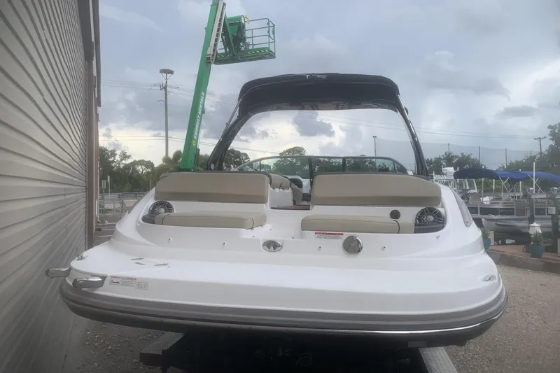 Slide: The Image of 2019 Rinker 29 QX boat, rear view, parked outdoors under cloudy sky. - 17