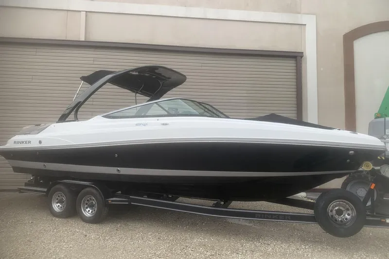 Slide: The Image of 2019 Rinker 29 QX boat on trailer, black and white design, parked outdoors. - 19
