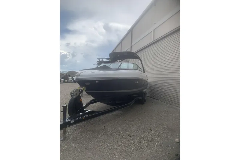 Slide: The Image of 2019 Rinker 29 QX boat on trailer, parked outdoors near a building. - 20