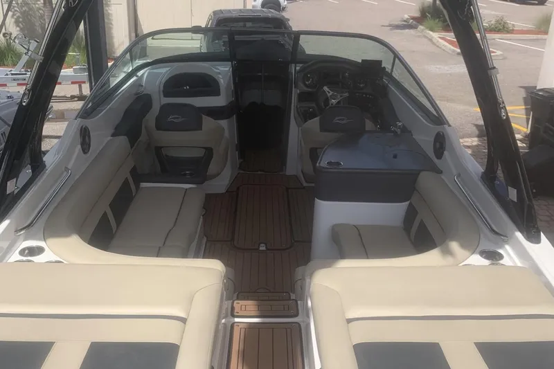 Slide: The Image of 2019 Rinker 29 QX boat interior with beige seating and wood flooring. - 8