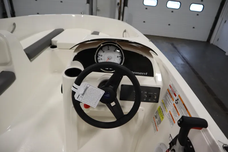 Slide: The Image of 2026 Bayliner Element E18 boat dashboard with steering wheel and controls in a garage. - 15