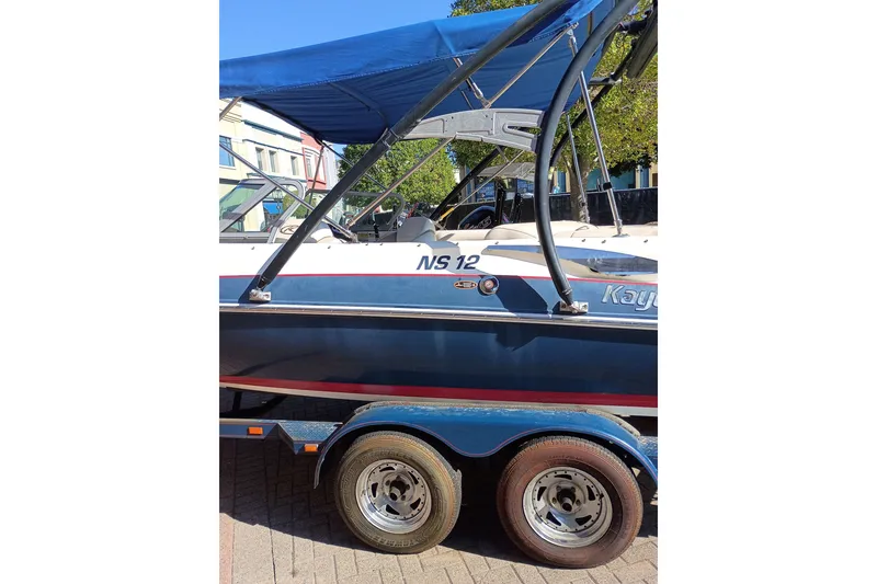 Slide: The Image of 2008 Harris-Kayot V200i boat with blue canopy on trailer, parked outdoors. - 13