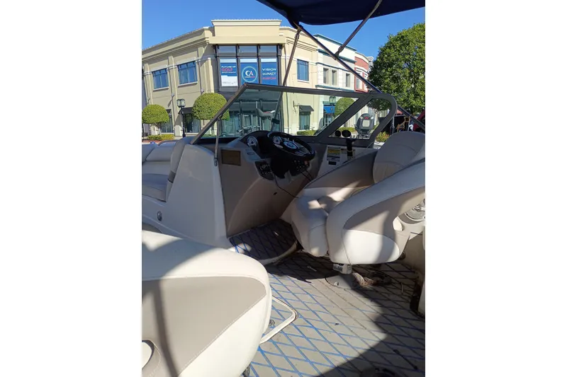 Slide: The Image of 2008 Harris-Kayot V200i boat interior with steering wheel and seating, parked near buildings. - 14
