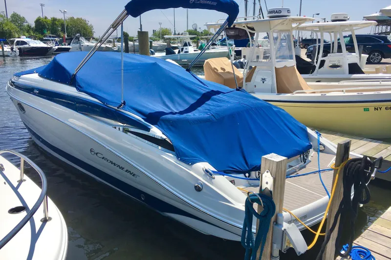 The Image of 2017 Crownline 275 SS boat docked with blue cover in a marina. - 0