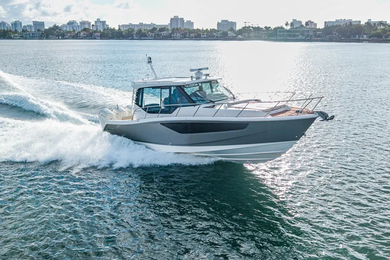 Slide: The Image of 2024 Boston Whaler 405 Conquest cruising on open water, city skyline in background. - 1