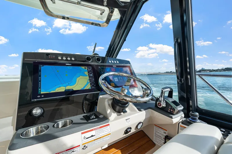 Slide: The Image of 2024 Boston Whaler 405 Conquest helm with navigation screens and steering wheel, on open water. - 25