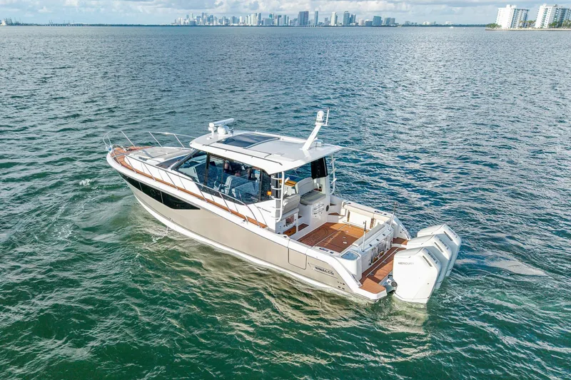 Slide: The Image of 2024 Boston Whaler 405 Conquest cruising on open water with city skyline backdrop. - 3
