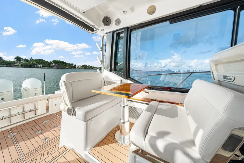 Slide: The Image of 2024 Boston Whaler 405 Conquest interior with seating and table, overlooking scenic waterfront. - 39