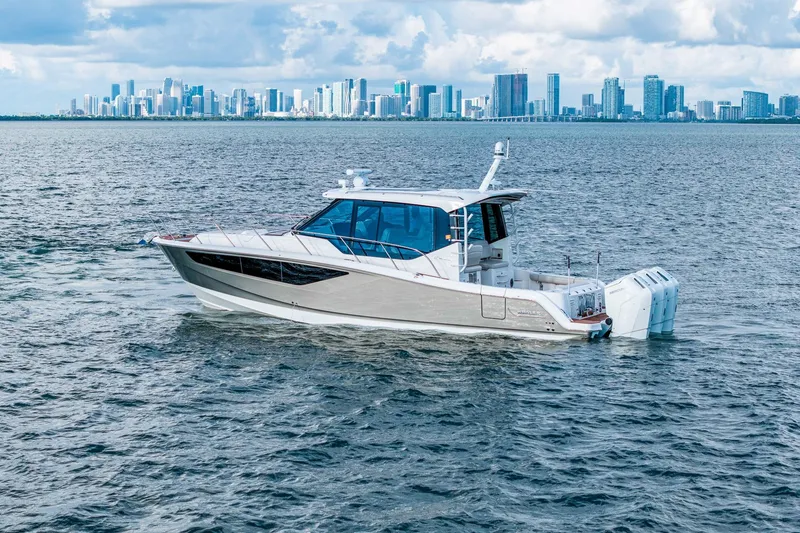Slide: The Image of 2024 Boston Whaler 405 Conquest cruising on water with city skyline backdrop. - 5