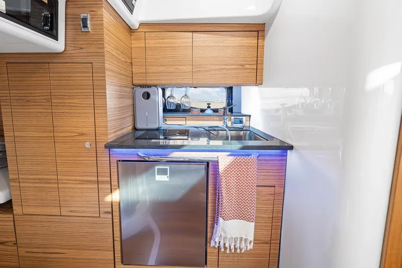 Slide: The Image of 2024 Boston Whaler 405 Conquest kitchen with wood cabinetry and modern appliances. - 53