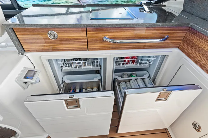 Slide: The Image of 2024 Boston Whaler 405 Conquest galley with open refrigerators and wooden cabinetry. - 54