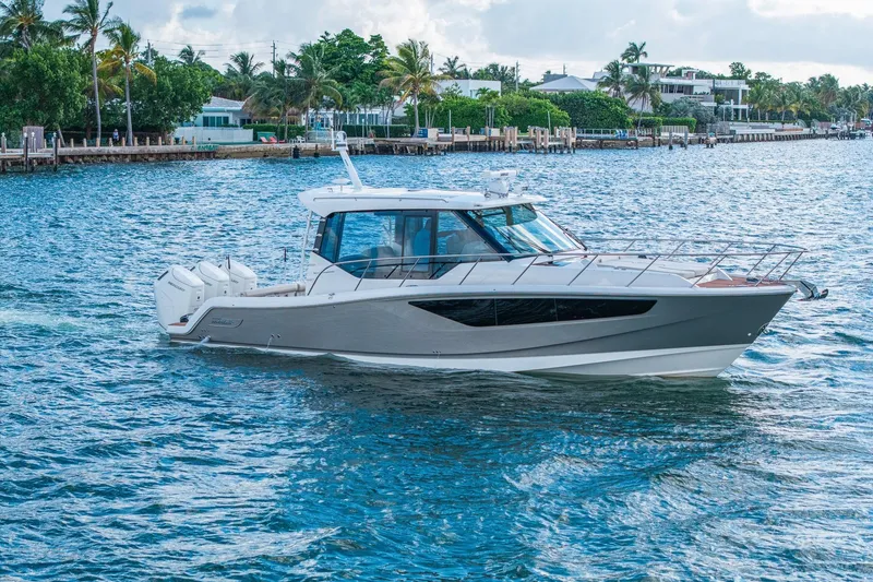 Slide: The Image of 2024 Boston Whaler 405 Conquest cruising on a scenic waterway with palm trees. - 63