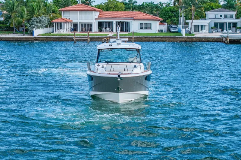 Slide: The Image of 2024 Boston Whaler 405 Conquest cruising on blue water near waterfront homes. - 64