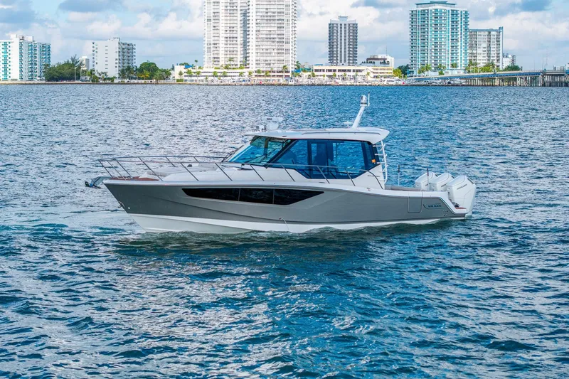 Slide: The Image of 2024 Boston Whaler 405 Conquest cruising on water with city skyline backdrop. - 65