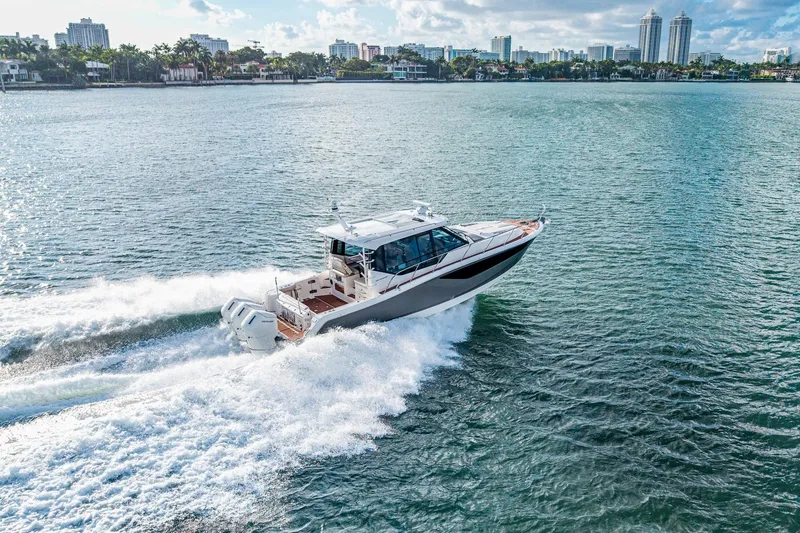Slide: The Image of 2024 Boston Whaler 405 Conquest cruising on open water, city skyline in background. - 69