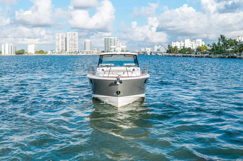 Slide: The Image of 2024 Boston Whaler 405 Conquest cruising on a sunny day with city skyline backdrop. - 7
