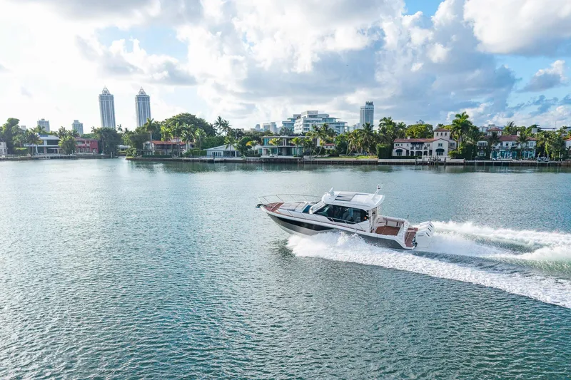 Slide: The Image of 2024 Boston Whaler 405 Conquest cruising on a scenic waterfront with city skyline. - 73