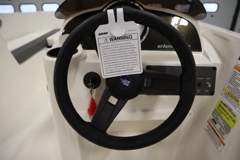 Slide: The Image of Steering wheel of 2026 Bayliner Element E18 boat with warning tag and control panel. - 16