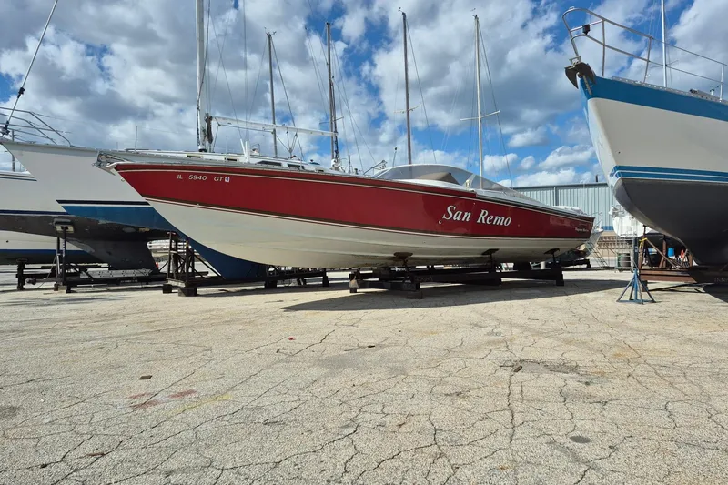 The Image of Red 1982 Magnum 40 boat named "San Remo" on dry dock under a cloudy sky. - 0
