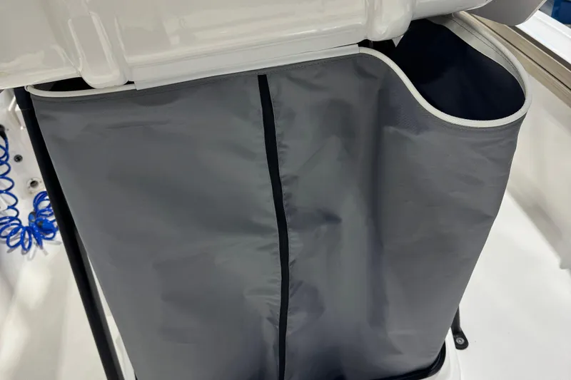 Slide: The Image of 2024 Yamaha Boats 190 FSH Sport storage compartment with gray fabric cover. - 11