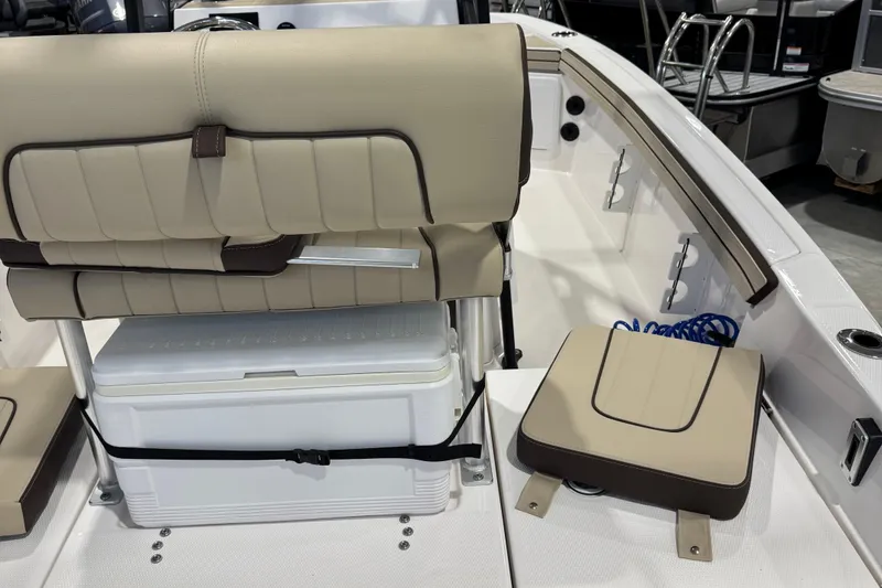 Slide: The Image of 2024 Yamaha Boats 190 FSH Sport interior with beige seating and storage area. - 2