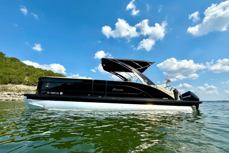 Slide: The Image of 2021 Barletta L25UC pontoon boat on a sunny lake with blue skies. - 1