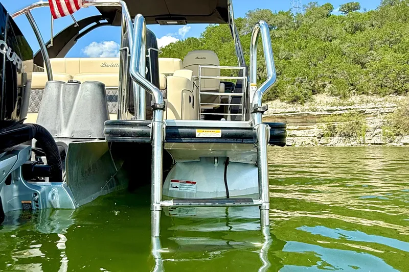 Slide: The Image of 2021 Barletta L25UC pontoon boat with ladder, floating on a scenic lake. - 11