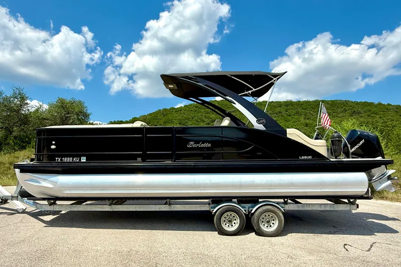 Slide: The Image of 2021 Barletta L25UC pontoon boat on trailer, under clear blue sky. - 17