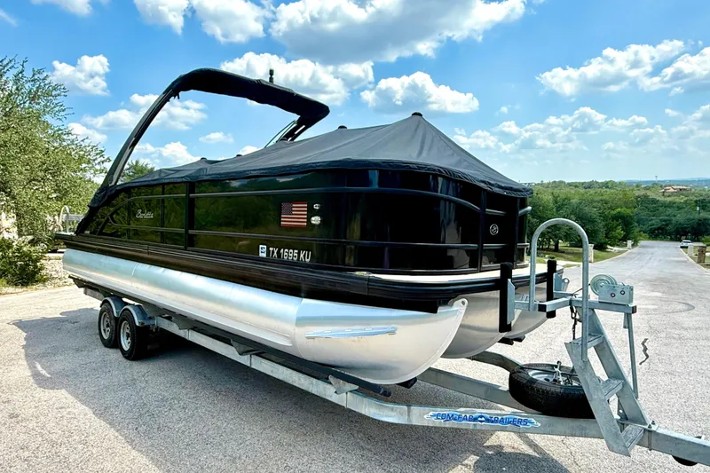 Slide: The Image of 2021 Barletta L25UC pontoon boat on trailer, covered, parked on a sunny day. - 19