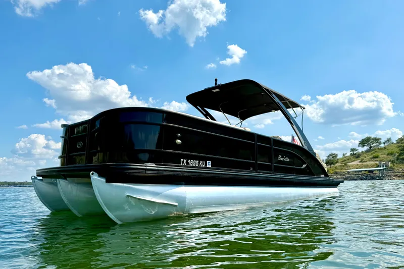 Slide: The Image of 2021 Barletta L25UC pontoon boat on a sunny lake with blue sky. - 2
