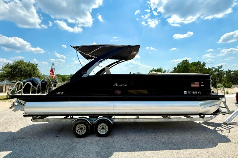 Slide: The Image of 2021 Barletta L25UC pontoon boat on trailer under a clear blue sky. - 20